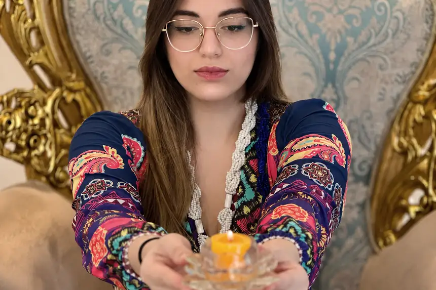 Taróloga Valentina segurando uma vela acesa em suporte de vidro durante um trabalho